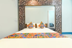 A hotel room with a bed, two pillows, a nightstand, and a mirror. - FabHotel Taj Palace (Kolkata)
