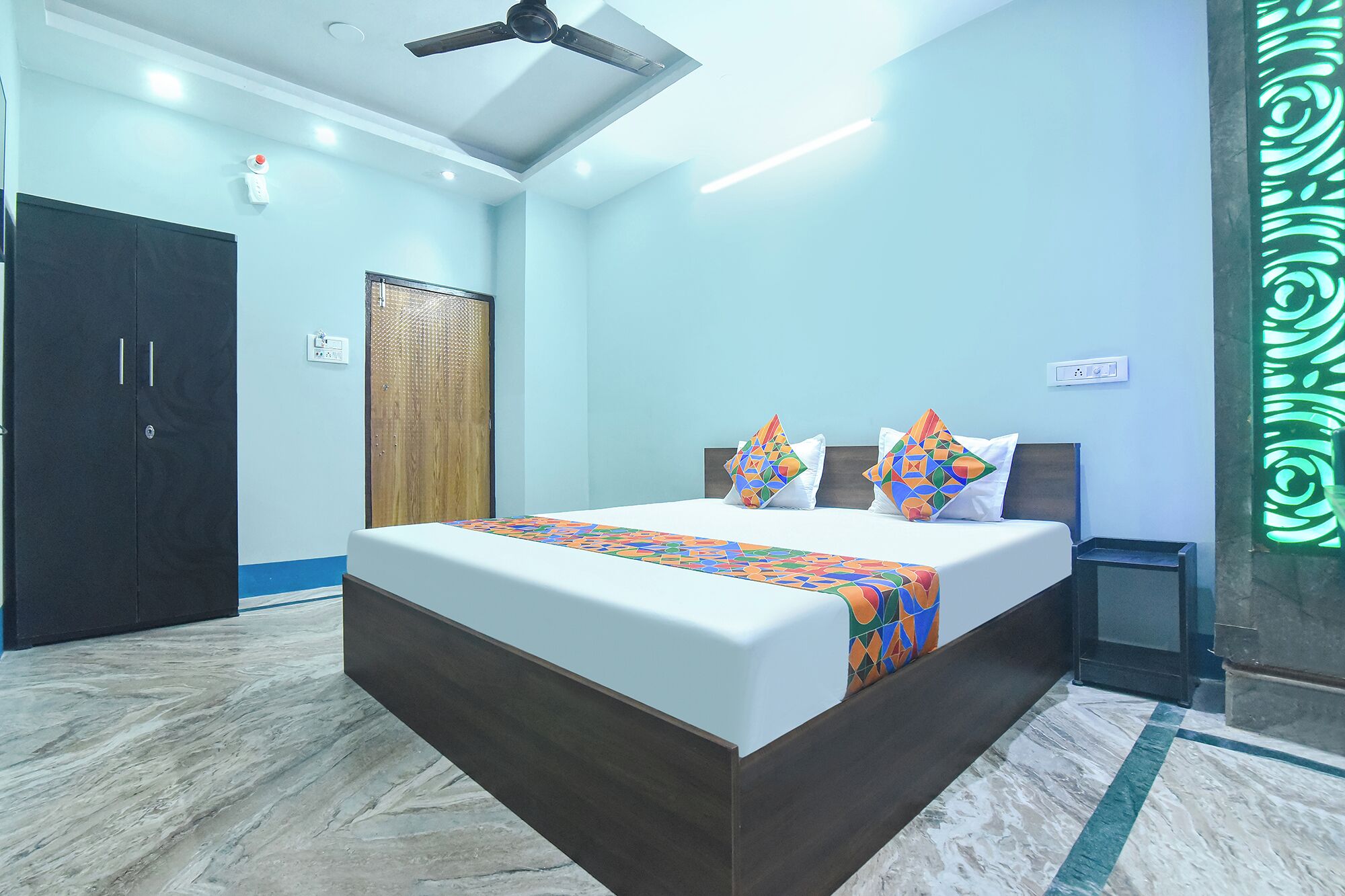 A bedroom with a bed, a wardrobe, a ceiling fan, and a decorative wall panel.