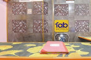 Un espace d’accueil d’hôtel avec une enseigne indiquant « fab hotels » et des panneaux métalliques décoratifs.