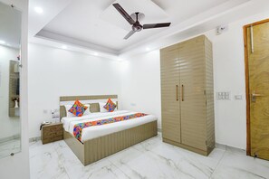 A bedroom with a bed, wardrobe, ceiling fan, and a door.