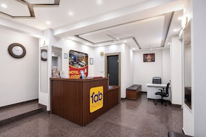 A hotel reception area with a reception desk, a clock, and a framed picture on the wall.