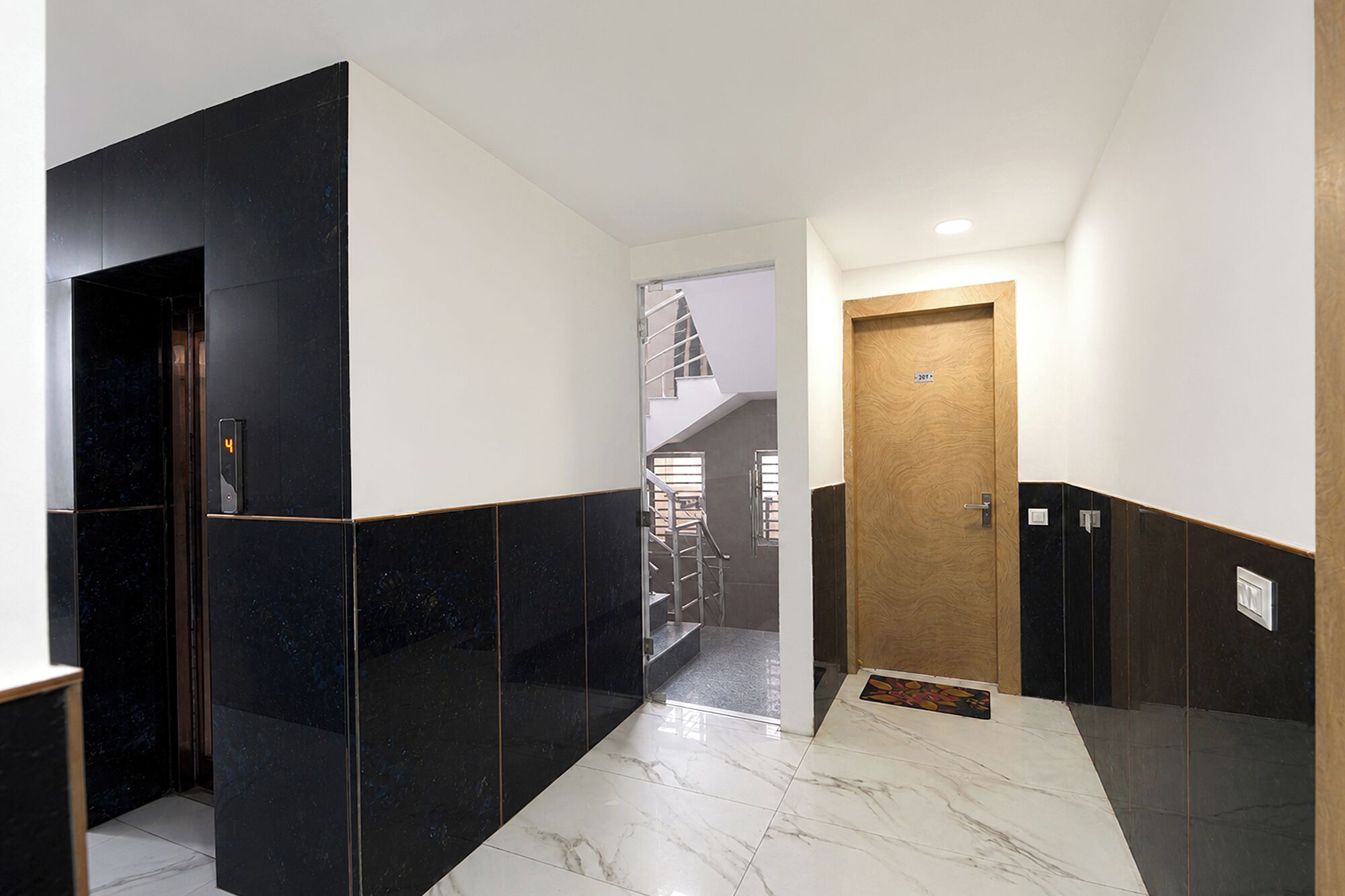 A hallway with a marble floor, black and white walls, and a wooden door.