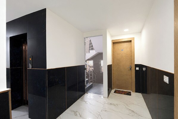A hallway with a marble floor, black and white walls, and a wooden door.
