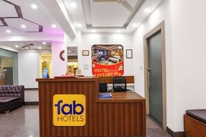 A hotel reception desk with a 'fab hotels' sign, a framed picture of a room, and a door to the right.