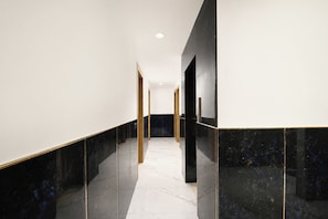 A modern hallway with marble flooring and walls, featuring a straight path and a door at the end.
