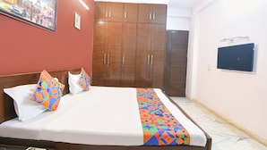 Una habitación de hotel con cama, armario, televisor y un cuadro en la pared.