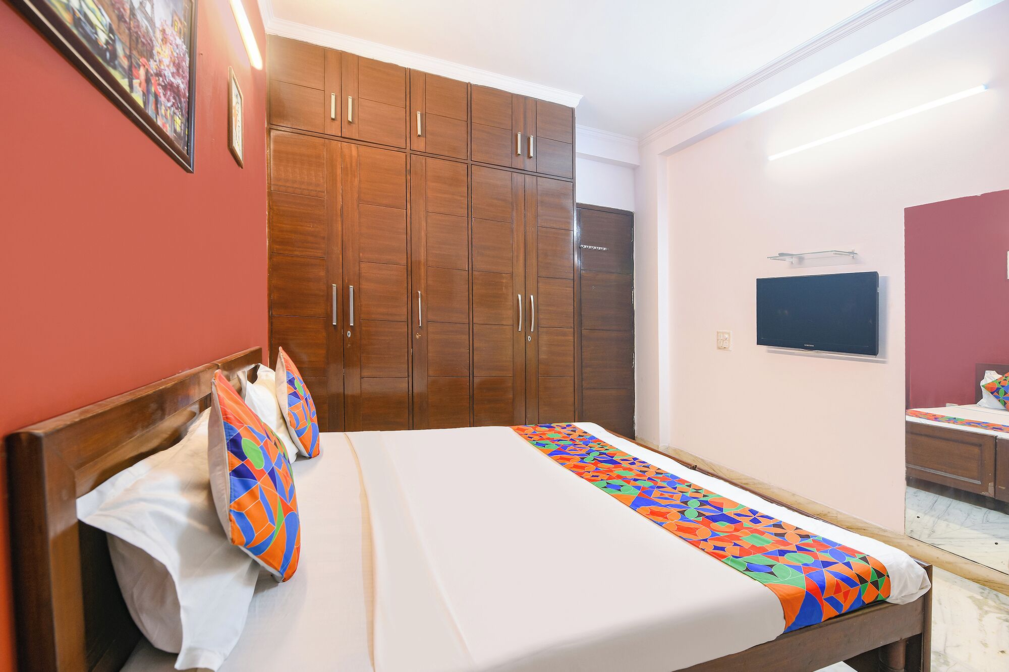 A hotel room with a bed, a wardrobe, a television, and a mirror.