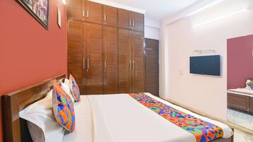 A hotel room with a bed, a wardrobe, a television, and a mirror.
