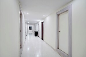 A long, narrow hallway with white walls and doors on both sides. - Fabhotel Saanvi Paradise (Bhopal)