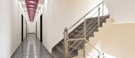 A modern interior with a straight staircase and a hallway leading to a door.