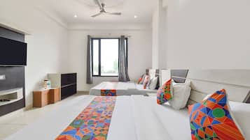 A hotel room with two beds, a TV, a ceiling fan, and a window with curtains.