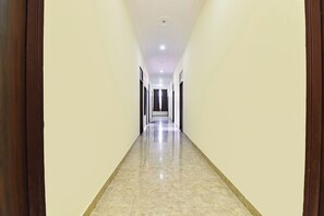Um corredor comprido e estreito com chão de azulejos brilhantes e paredes claras.