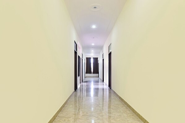 Un pasillo largo y estrecho con suelo brillante, puertas a ambos lados y un techo con luces empotradas.