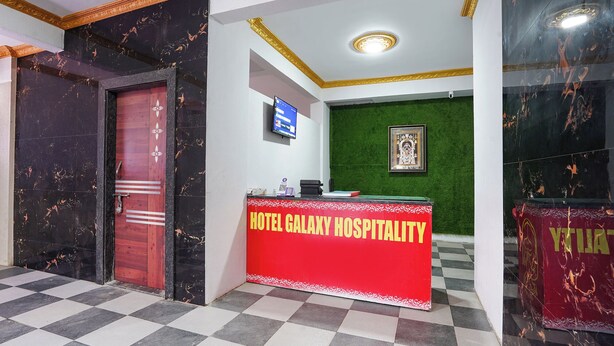 A reception desk with a sign reading 'HOTEL GALAXY HOSPITALITY' and a green wall with a framed picture. - Fabhotel Galaxy Stay (Pune)