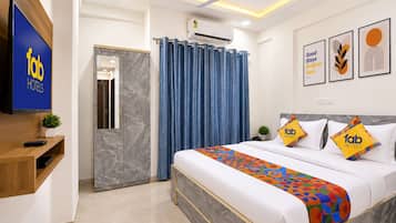 A hotel room with a bed, a TV, a ceiling fan, and a bathroom with a shower curtain.