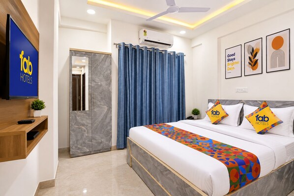 A hotel room with a bed, a TV, a ceiling fan, and a bathroom with a shower curtain.