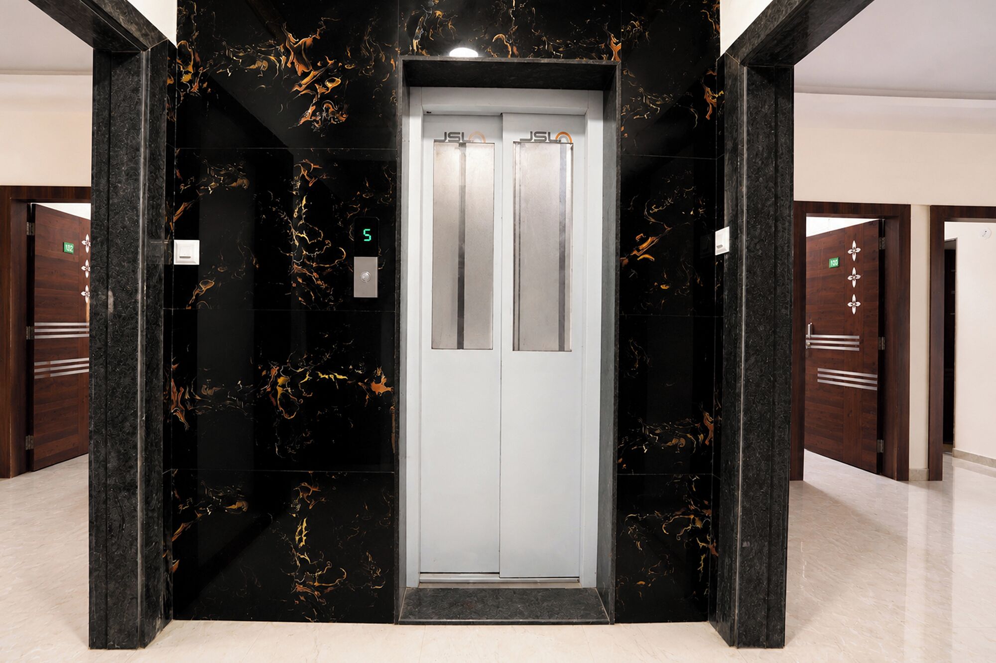 An elevator with a marble wall and a digital display showing the number 5.