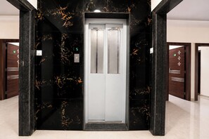An elevator with a marble wall and a digital display showing the number 5.