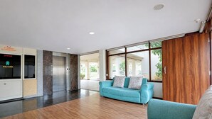 Un vestíbulo amplio con suelo de madera, un sofá azul y un armario de madera.