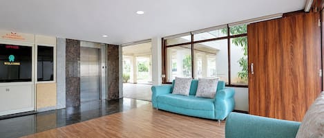 A spacious lobby with a wooden floor, a blue sofa, and a wooden wardrobe.