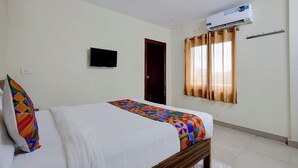 Una habitación de hotel con una cama, un equipo de aire acondicionado, un televisor y una puerta.