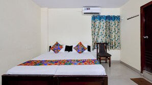 A bedroom with a bed, an air conditioning unit, a chair, and a door. - Fabhotel Ramnivas (Visakhapatnam)