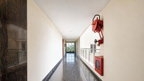 A corridor with a polished floor, a fire extinguisher mounted on the wall, and a door at the end. - Fabhotel Ramnivas (Visakhapatnam)