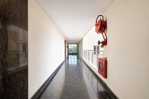 A corridor with a polished floor, a fire extinguisher mounted on the wall, and a door at the end.