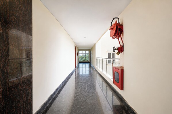 Un pasillo con piso pulido, un extintor de incendios montado en la pared y una puerta al final.