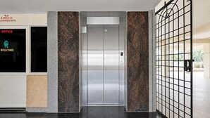 An elevator with a metallic finish, flanked by textured walls and a metal gate. - Fabhotel Ramnivas (Visakhapatnam)