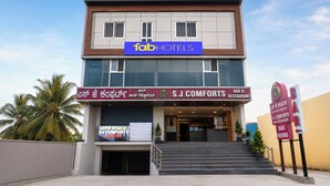 A modern building with a sign for 'fabHOTELS' and 'S.J. COMFORTS BAR & RESTAURANT' on the ground floor. - Fabhotel Sj Comforts (Bangalore)