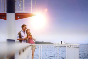 A couple standing on a pier with a body of water and a lighthouse in the background. - Modernes Apartment mit Blick auf den Hafen in Rechlin (Rechlin)