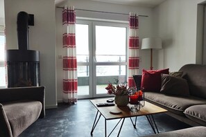 A living room with a fireplace, a sofa, a coffee table, and a view through a glass door. - Modernes Apartment mit Blick auf den Hafen in Rechlin (Rechlin)