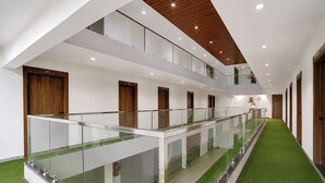 Ein mehrgeschossiges Hotelinnere mit Glastrennvorrichtungen, Holztüren und einem Korridor mit grünem Kunstrasen.