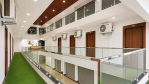 A hotel corridor with multiple rooms, a glass railing, and artificial grass flooring. - FabHotel Nashik Prime Stay (Nashik)