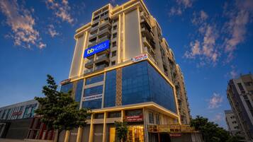 Et hotel med flere etager, hvor der hænger et tydeligt skilt med 'Fab Hotels', en 'Shivalik Comfort Stay' betegnelse og 'Yogeshwar Group' branding.