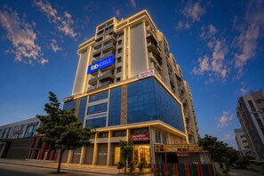 Un hotel de varios pisos con un llamativo letrero de 'Fab Hotels', una etiqueta de 'Shivalik Comfort Stay' y la marca 'Yogeshwar Group'.