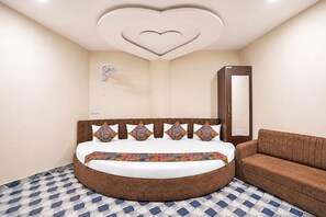 Quarto com cama redonda, design de teto em formato de coração, ventilador e guarda-roupa.