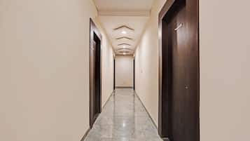 A corridor with a marble floor, wooden doors, and a ceiling with recessed lighting.