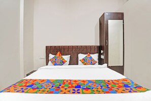 Una cama con una colcha estampada, dos almohadas con diseños geométricos y un cabecero de madera.