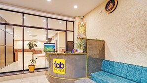 Een hotel receptie met een receptiebalie, een klok en een blauwe bank.