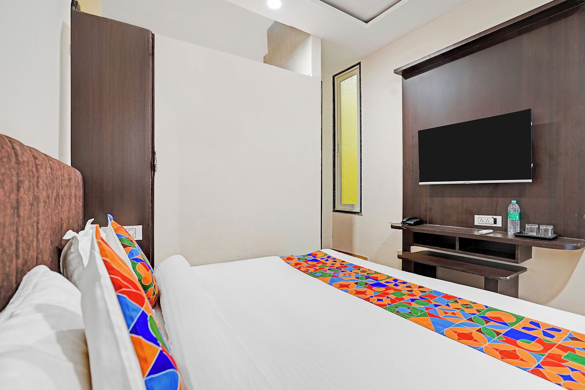 Habitación de hotel con cama, televisión montada en la pared y ventana con vistas.