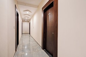 A hallway with a marble floor, a wooden door, and a ceiling with recessed lighting. - Fabhotel Shivlok (Bhopal)