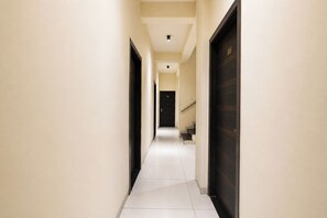 A corridor with a door at the end, a staircase to the right, and a light fixture on the ceiling. - FabHotel Shree I (Indore)