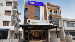 Un hotel llamado Veloura con un café y restaurante, un letrero de Fab Hotels y vistas de los edificios circundantes.