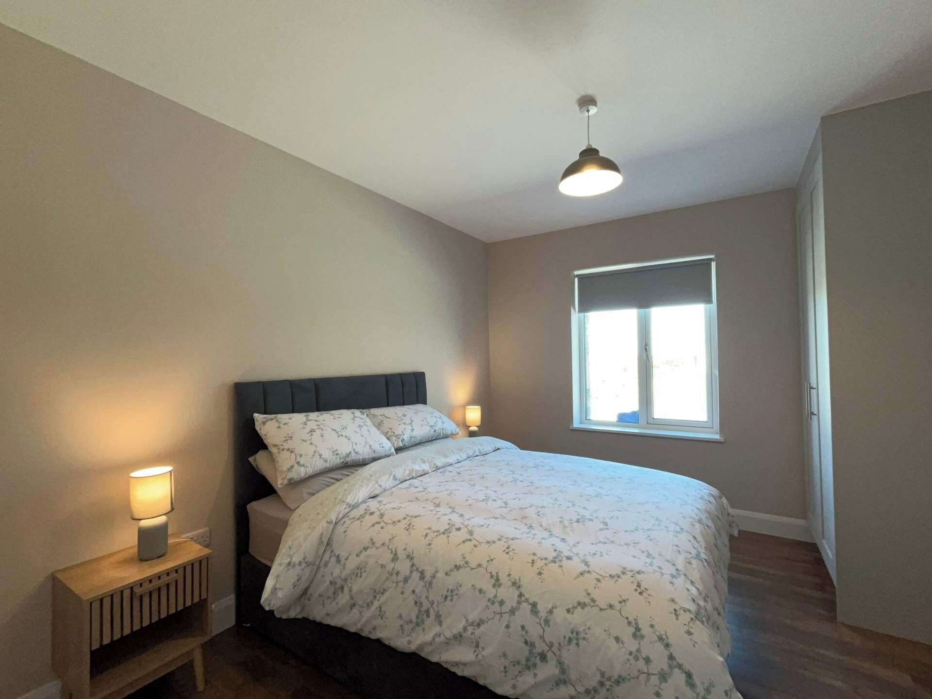A bedroom with a bed, bedside lamps, a window, and a ceiling light.
