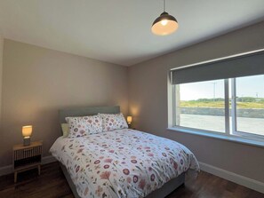 Ein Schlafzimmer mit einem Bett, einem Fenster und einer Lampe.