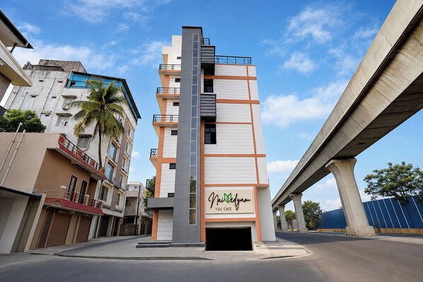 A modern building with a sign for 'Nai Veg Cafe' on the ground floor.