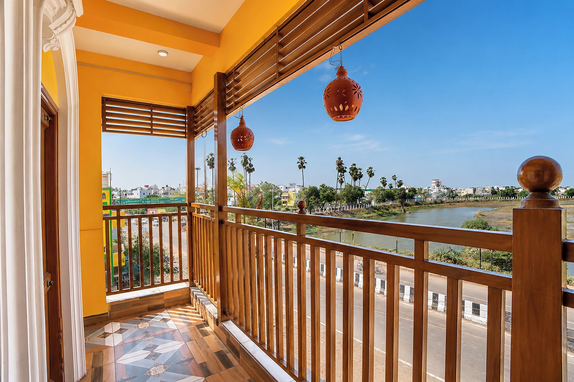 Un balcón con vista a un río, palmeras y un paisaje urbano.