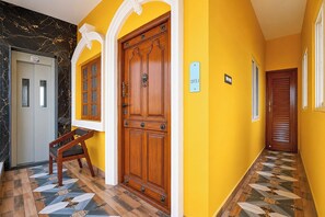 A hallway with a wooden door, a bench, and a tiled floor. - FabHotel Le Pondy (Puducherry)